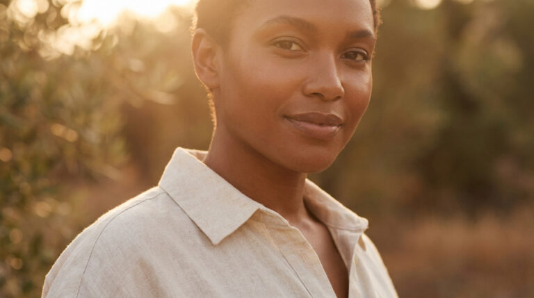 Portrait d'une femme au teint mat rayonnante sous la lumière dorée du soleil.